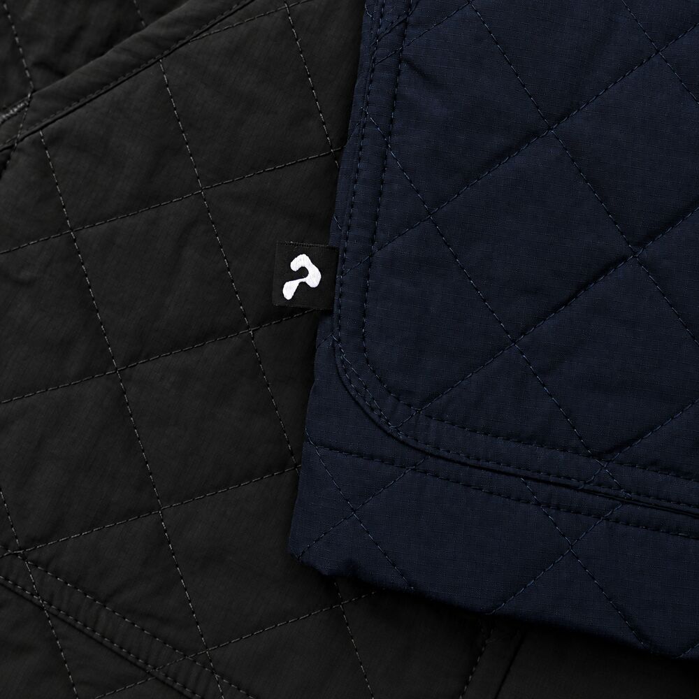 A small woven Ponda tab stitched at the hem between two quilted panels